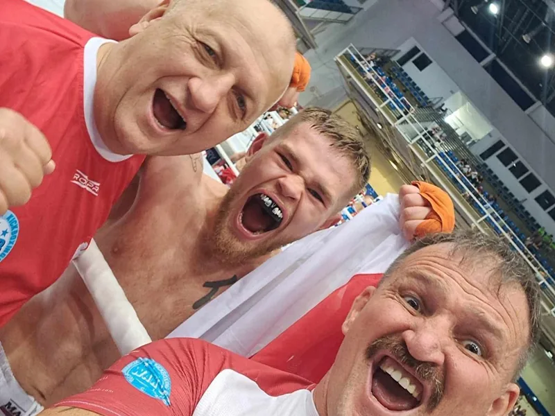 Janek Matyjaszczyk z trenerami kadry po wygranej walce, z biało-czerwoną flagą